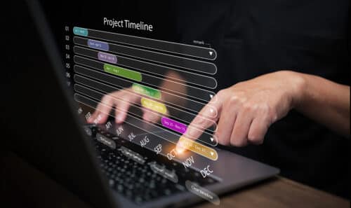 A man, with his laptop computer, using a project timeline to ensure timely completion. Project management concept